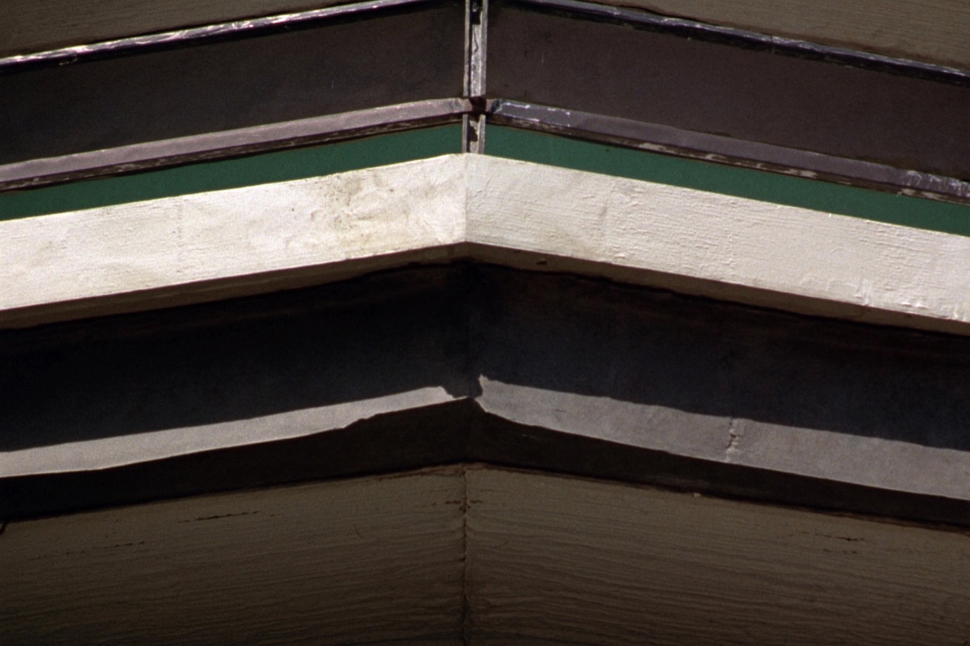 Close detail of a concrete balcony slab edge showing the waterproof deck coating and metal drip flashing above the soffit below