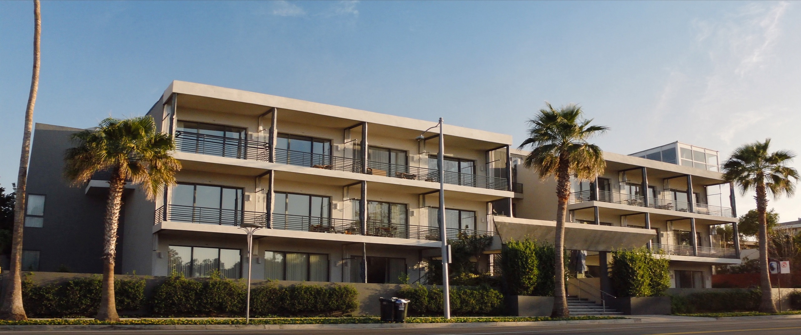Three-story multifamily condominium building in San Diego County with stacked cantilevered balconies along the facade